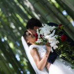 Due sposi si baciano in mezzo a un canneto. In primo piano il bouquet della sposa. L'inquadratura è volutamente inclinata a 45° e gli sposi vengono "tagliati" dal bordo della foto nell'angolo in basso a destra