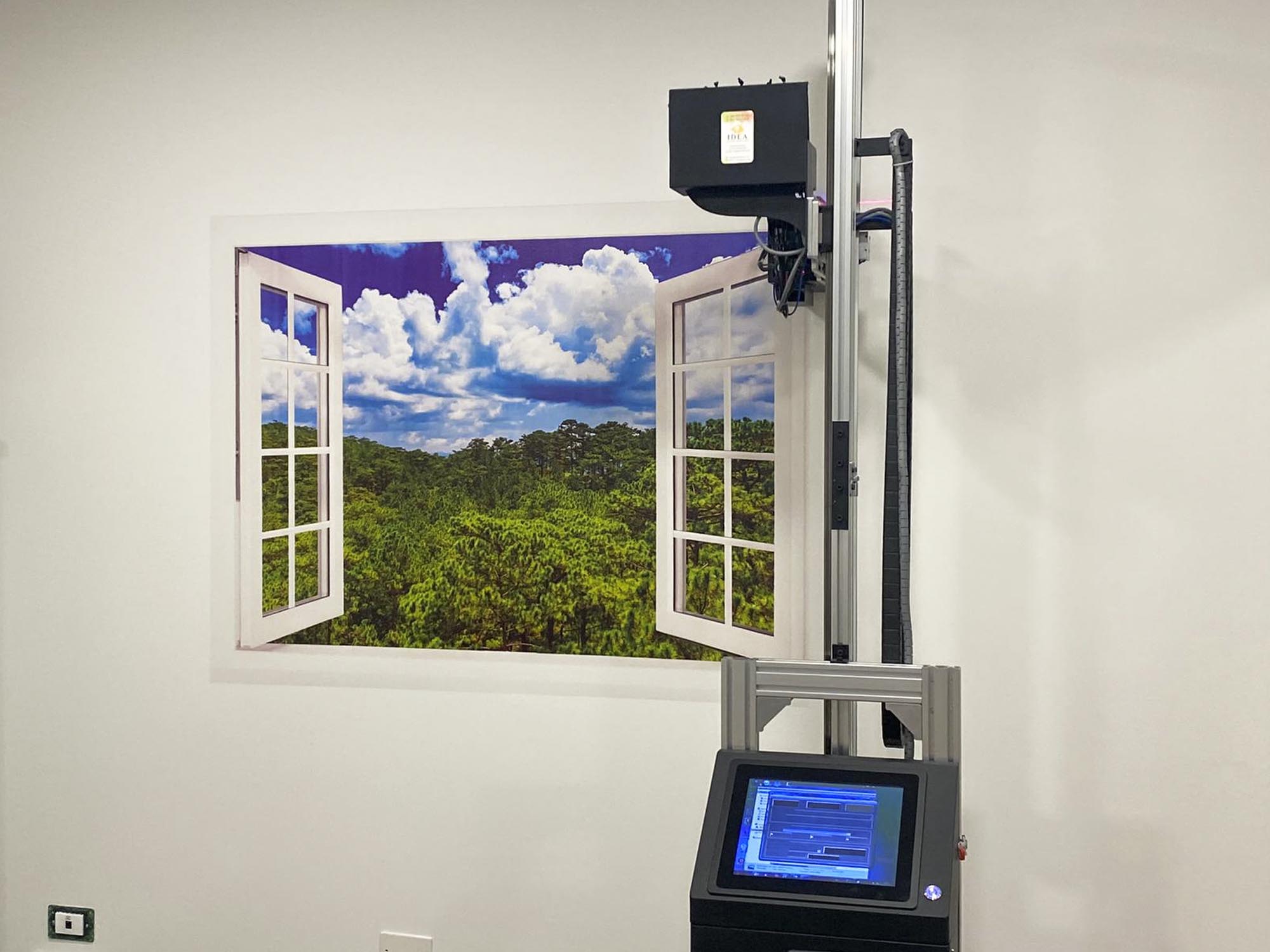Wally la stampante da muro con la stampa di una finestra che si apre su un bosco e con sopra un cielo blu con nuvole bianche
